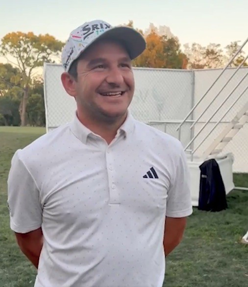 Smiling man wearing a golf cap and polo shirt outdoors.