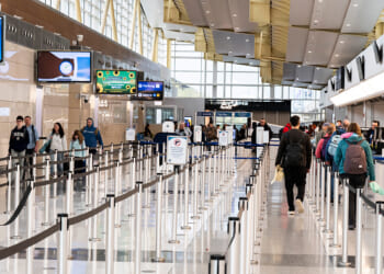 Travelers walk in the lines of Ronald Reagan International Airport on March 30, 2026.