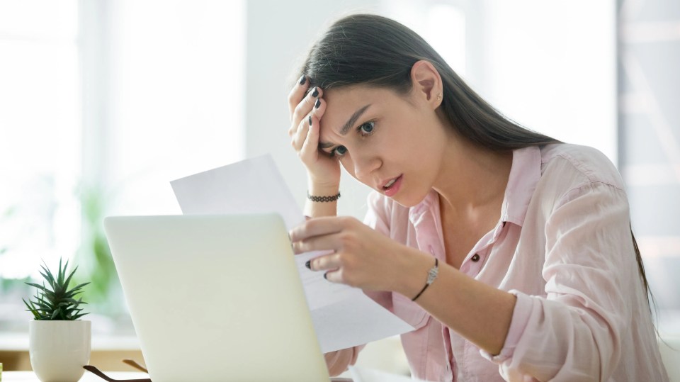 A stressed woman looks at upsetting paperwork.