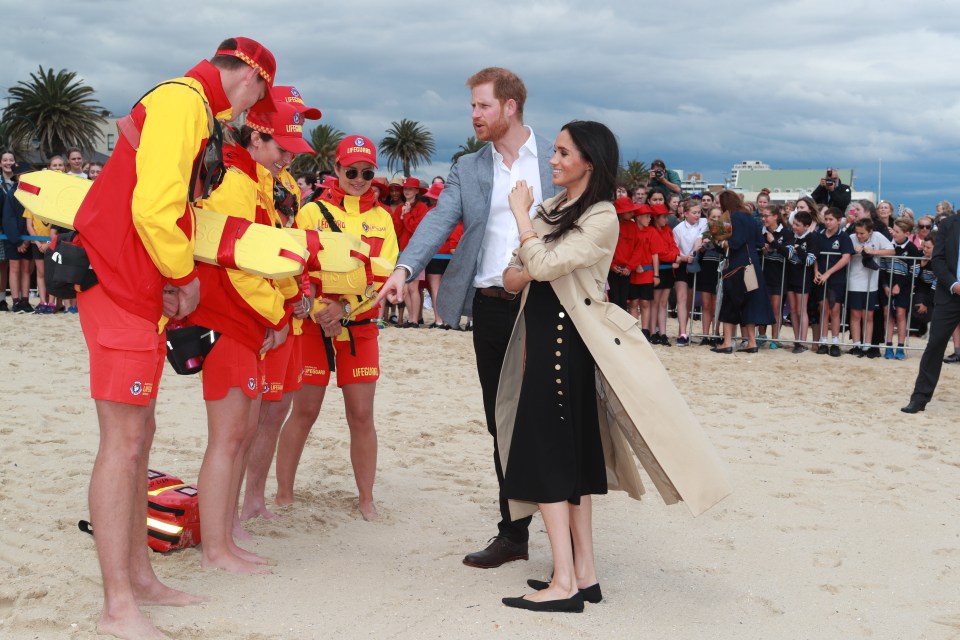 The Duke and Duchess of Sussex chatting with lifeguards on a beach.