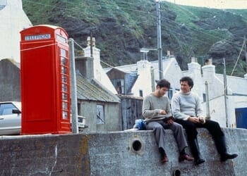 Mod con: Local Hero actors Peter Rieghert and Chris Rozycki sitting on the harbour wall by Pennan¿s famous red phone box, which still draws tourists to the village