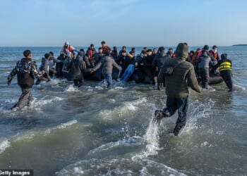 Migrants sprint through the surf at Gravelines beach in northern France last week to board a dinghy to Britain