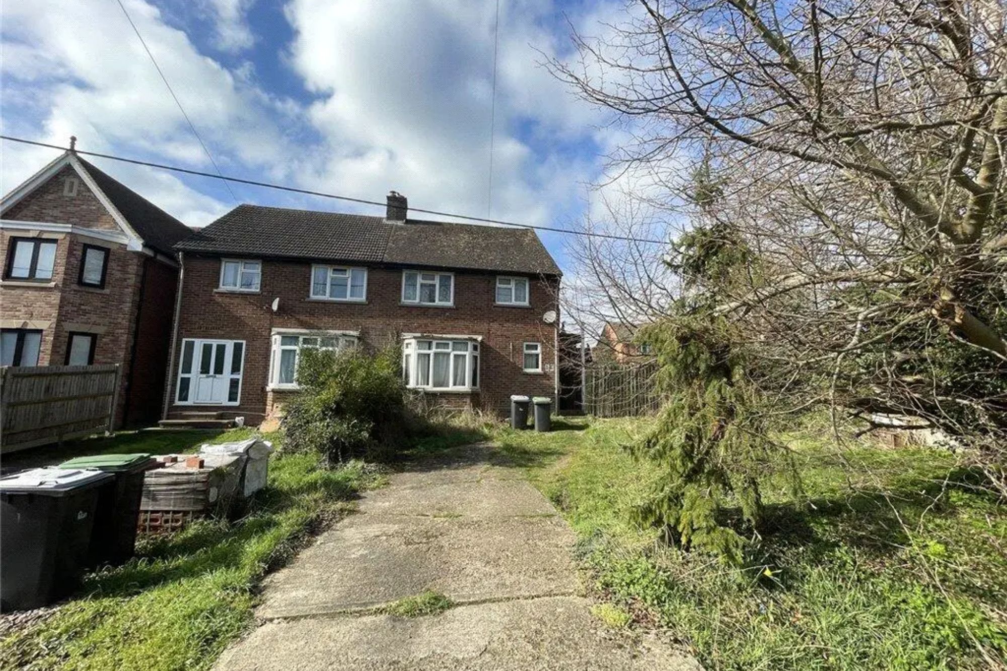 An image collage containing 1 images, Image 1 shows Exterior of a brick house with white windows and doors, with an unkempt yard and a concrete driveway