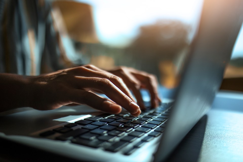 Close-up of hands typing on a laptop keyboard.