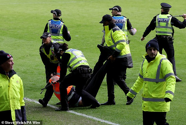 An injured steward is carried from the pitch as police struggle to restore order at Ibrox