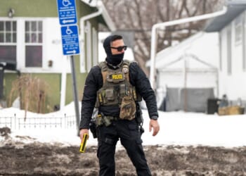 An ICE agent holds a taser as he stands watch after one of their vehicles got a flat tire on Penn Avenue on Feb. 5, 2026, in Minneapolis, Minnesota.