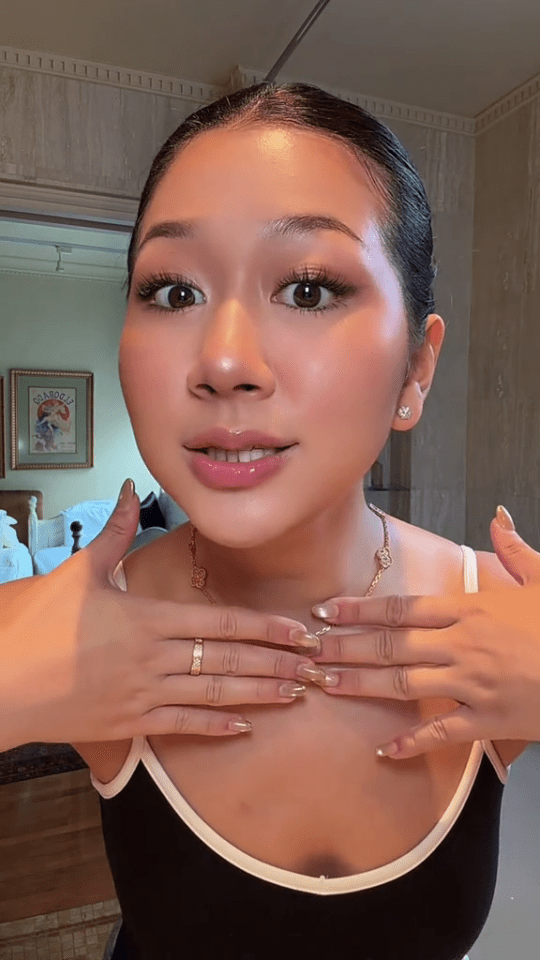 A young woman with a black top and gold jewelry.