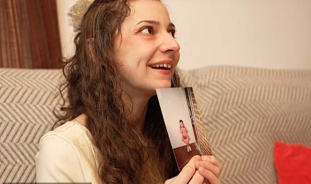Noelia smiles as she holds up a picture from her childhood taken before her life was marked by abuse and trauma