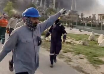 Pictured: Workers evacuate area around Saudi Aramco's Ras Tanura oil refinery as smoke rises following a reported Iranian drone strike