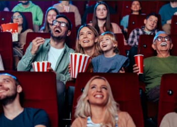 A crowd in a movie theater laughing at what they're watching.
