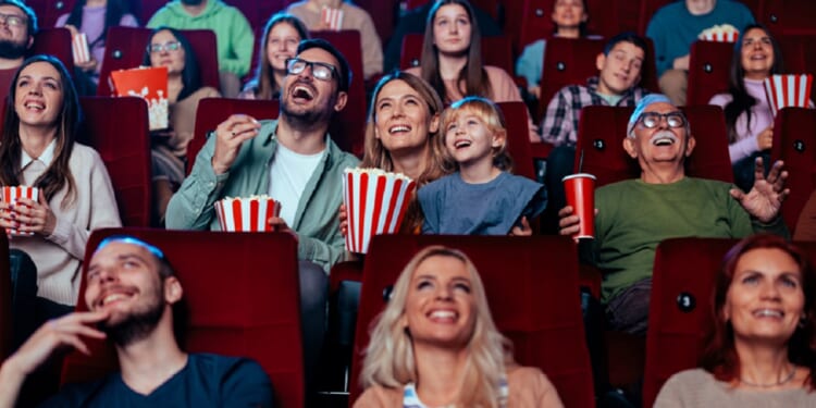 A crowd in a movie theater laughing at what they're watching.