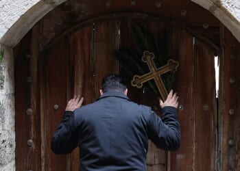 Issa Kassissieh (pictured), a Palestinian Christian who is popular for being the Santa Claus of the city, stands holding a cross and a palm frond at the doors of the Church of the Holy Sepulchre after finding them locked, following the cancellation of the traditional Palm Sunday procession from the Mount of Olives