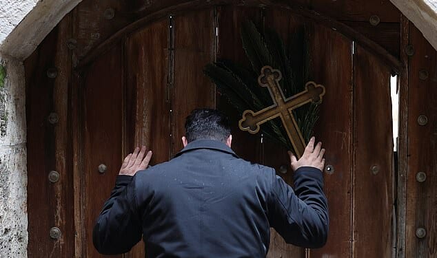 Issa Kassissieh (pictured), a Palestinian Christian who is popular for being the Santa Claus of the city, stands holding a cross and a palm frond at the doors of the Church of the Holy Sepulchre after finding them locked, following the cancellation of the traditional Palm Sunday procession from the Mount of Olives