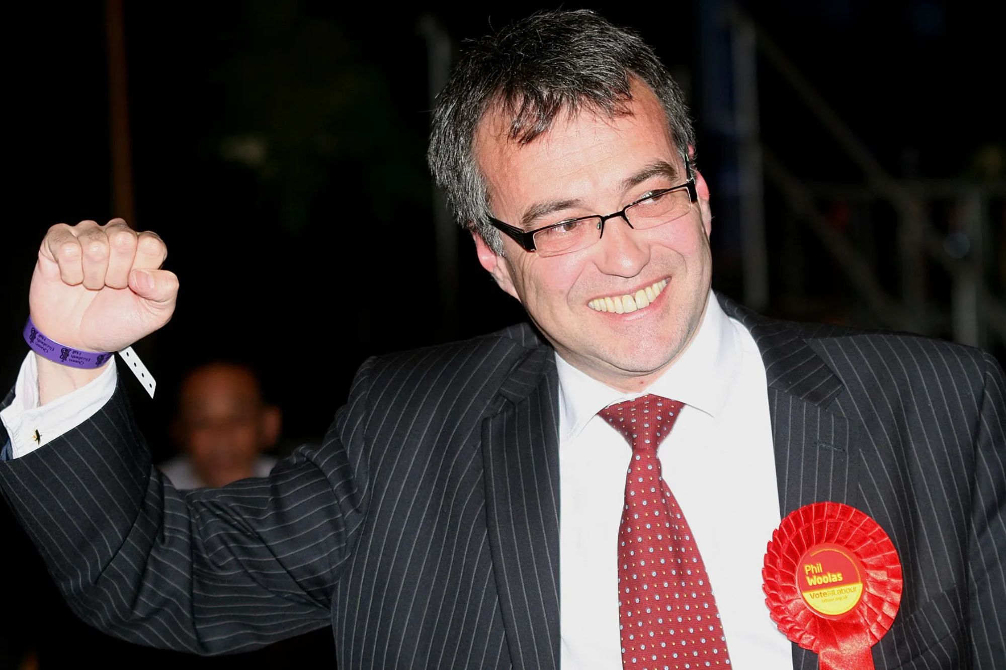 An image collage containing 1 images, Image 1 shows Phil Woolas MP smiles and punches the air after retaining his seat in the 2010 General Election