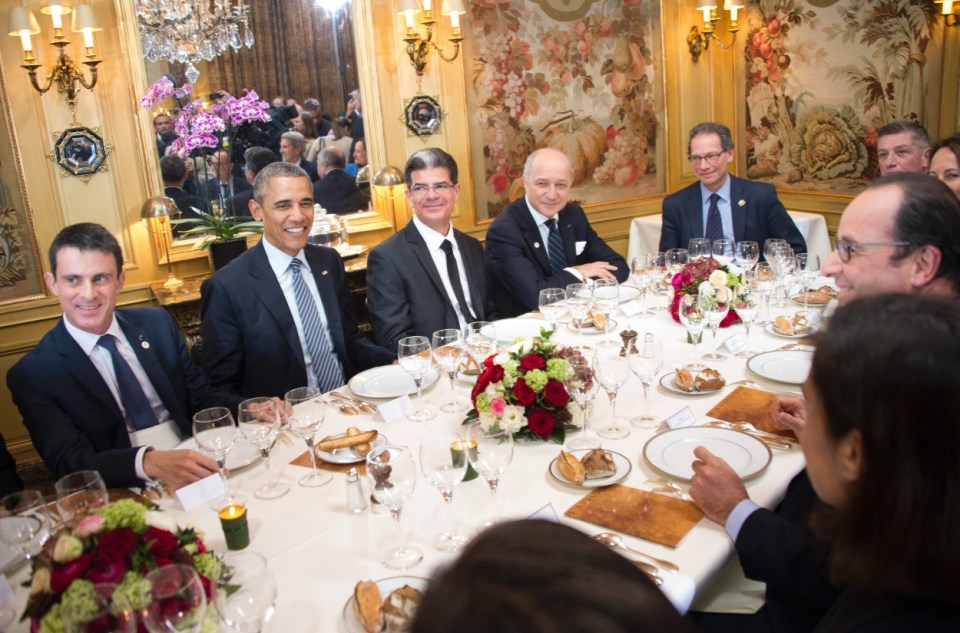 Barack Obama, Manuel Valls, and other world leaders sitting around a formal dinner table.