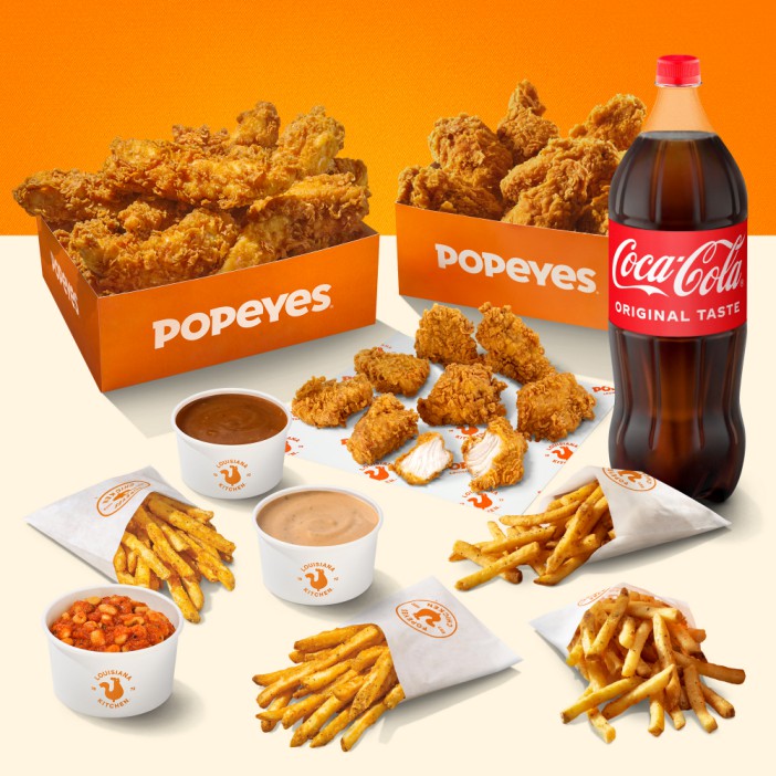Popeyes fried chicken, fries, sauces, and a bottle of Coca-Cola.