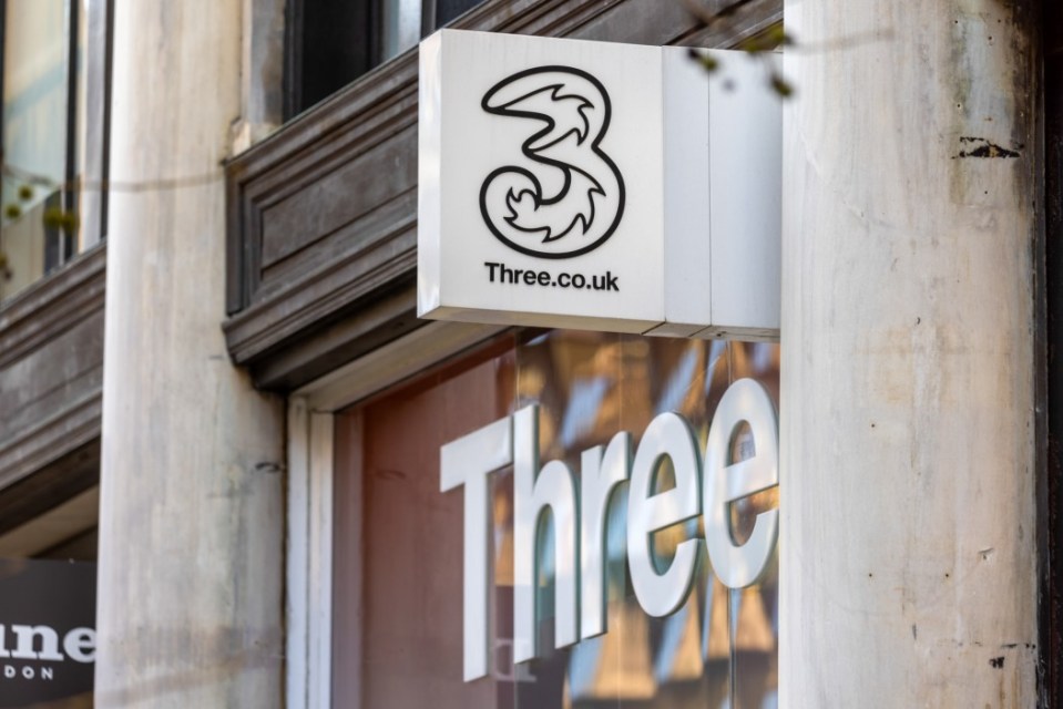 Sign for Three.co.uk above a shop window with the word "Three" on it.