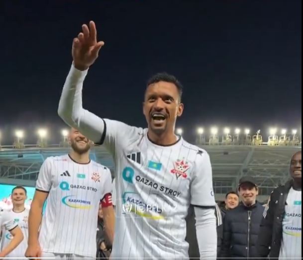A smiling Nani waves to fans in a white and black soccer jersey.