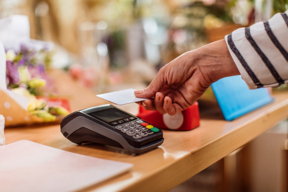 Person making a contactless payment with a credit card at a flower shop.