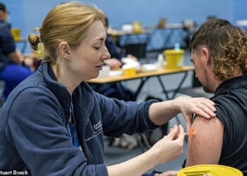 An infectious diseases expert tonight called for public health officials to reconsider a meningitis B vaccination drive for adolescents. Pictured: A young man receives a meningitis vaccination at the University of Kent