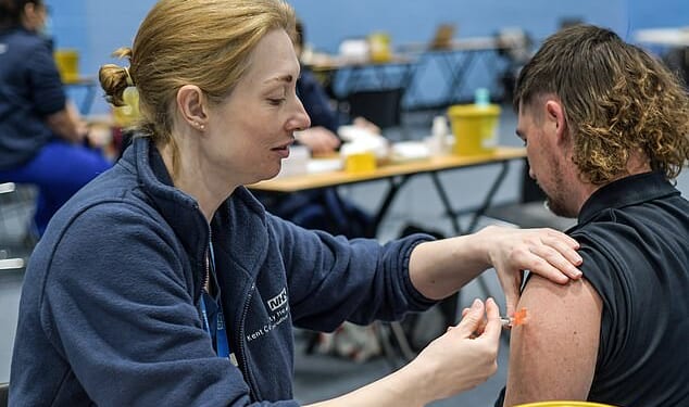 An infectious diseases expert tonight called for public health officials to reconsider a meningitis B vaccination drive for adolescents. Pictured: A young man receives a meningitis vaccination at the University of Kent
