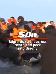 Migrants sprint across beach and pack  into dinghy