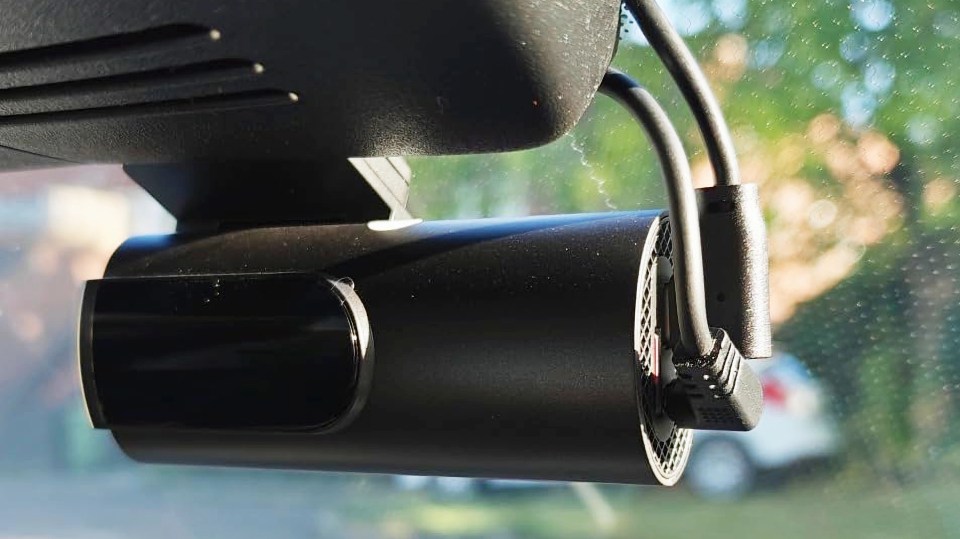 Black GK U dash cam mounted inside a car, with the outside view visible through the windshield.