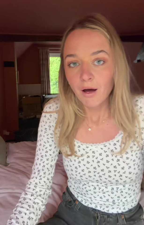 A blonde woman in a white floral top with an open mouth expression.