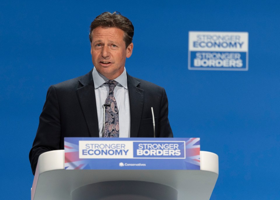 Nigel Huddleston speaking at the Conservative Party Conference, with "Stronger Economy, Stronger Borders" on the podium and background.