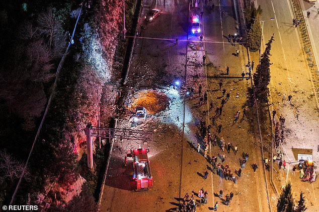 Israeli emergency responders work at the scene of an Iranian missile strike in Jerusalem on March 1, 2026, with a huge crater clearly visible in the road