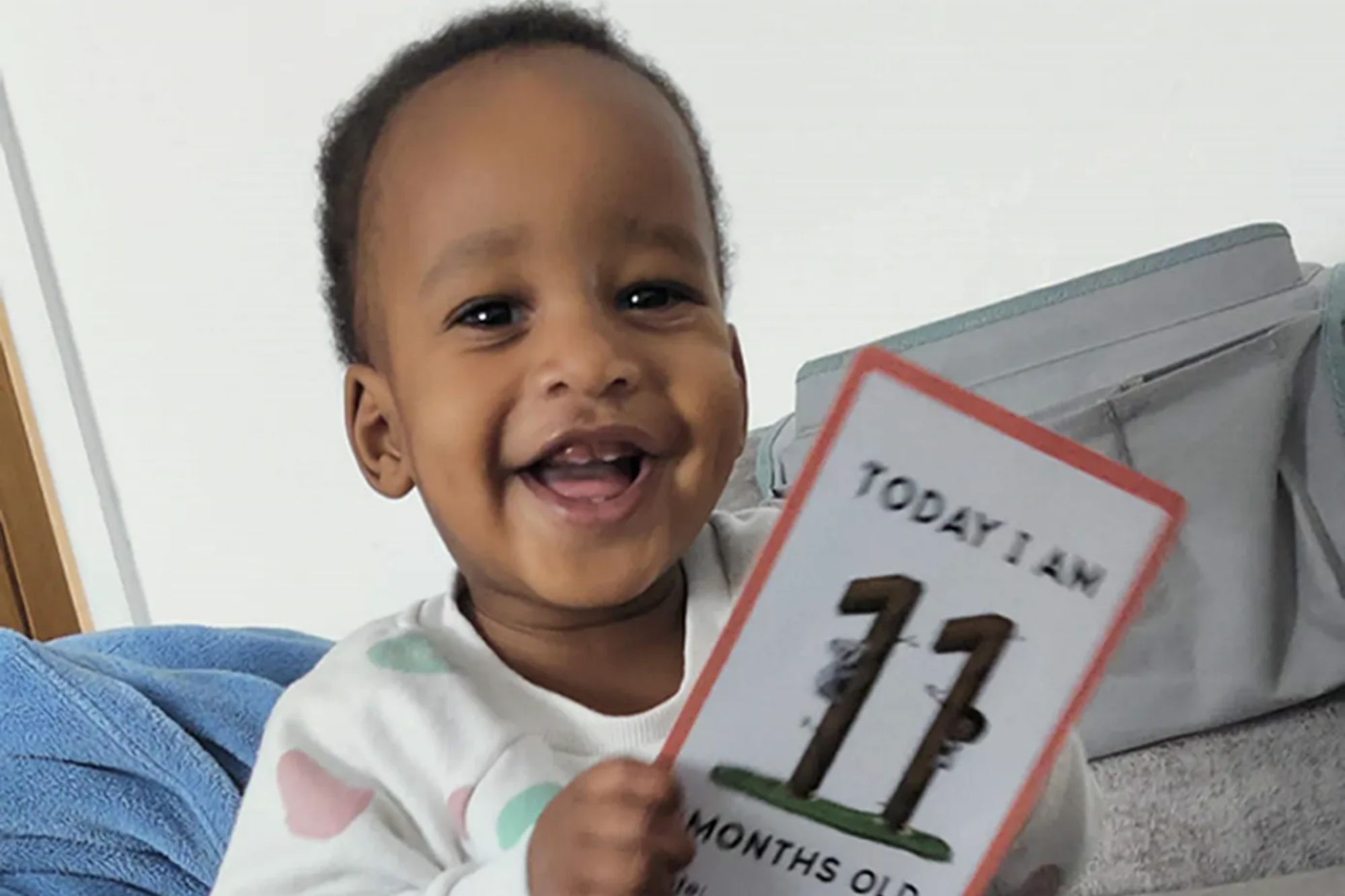 An image collage containing 1 images, Image 1 shows Noah Sibanda, a smiling baby, holds a card that reads "Today I am 11 months old."