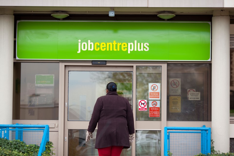 A woman facing the doors of a Job Centre Plus building.