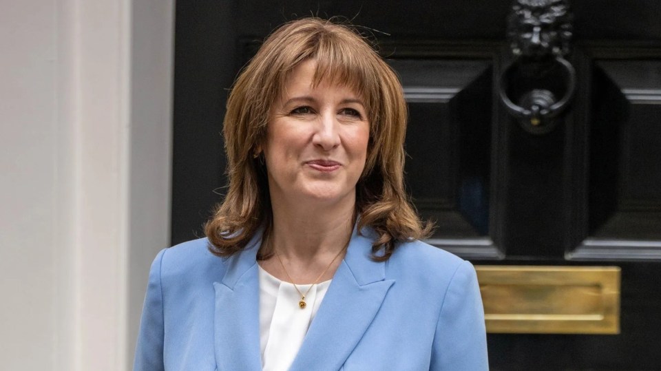 Rachel Reeves, Chancellor of the Exchequer, in a blue pantsuit, holding a red folder, stands outside 11 Downing Street.