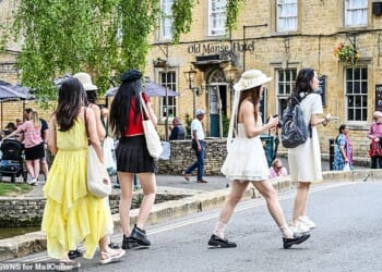 A group of women walk near picturesque buildings in Bourton-on-the-Water in summer last year