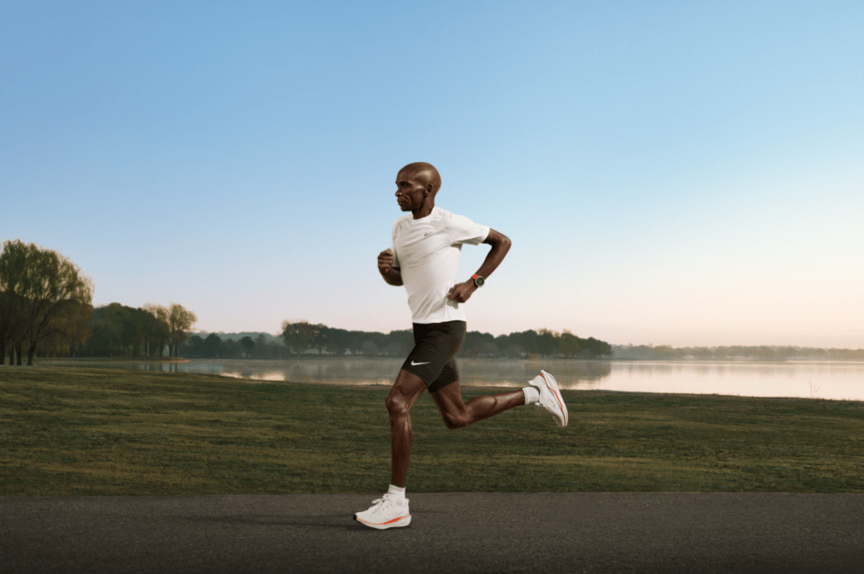 Eliud Kipchoge running in white attire with a smartwatch.