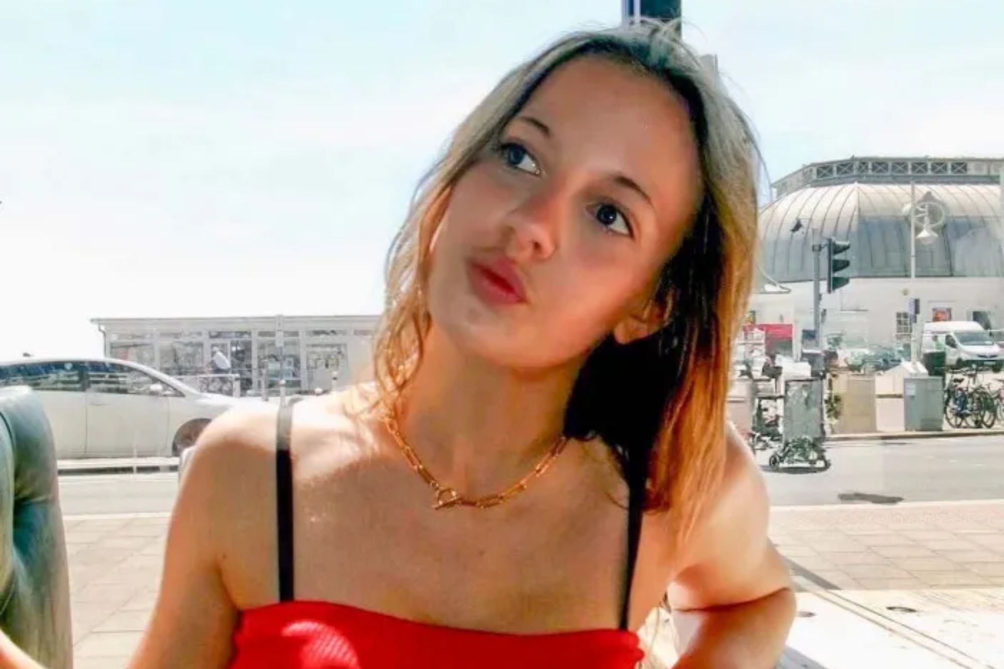 An image collage containing 1 images, Image 1 shows A young woman in a red dress looking up and to her right, outdoors on a sunny day