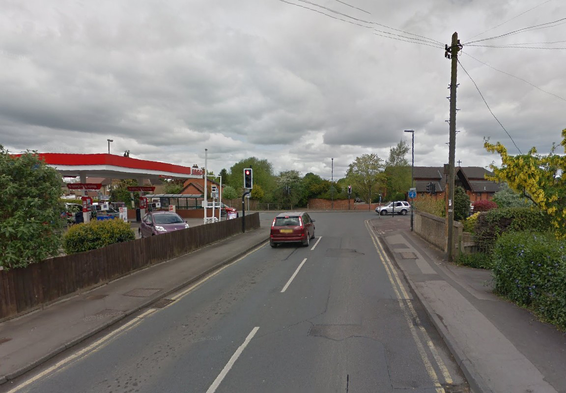 An Esso garage with cars on a street under a cloudy sky.