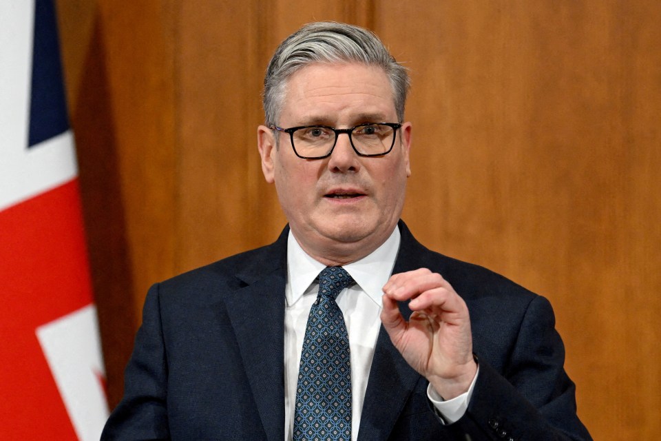 British Prime Minister Keir Starmer speaking at a podium with a Union Jack flag behind him.
