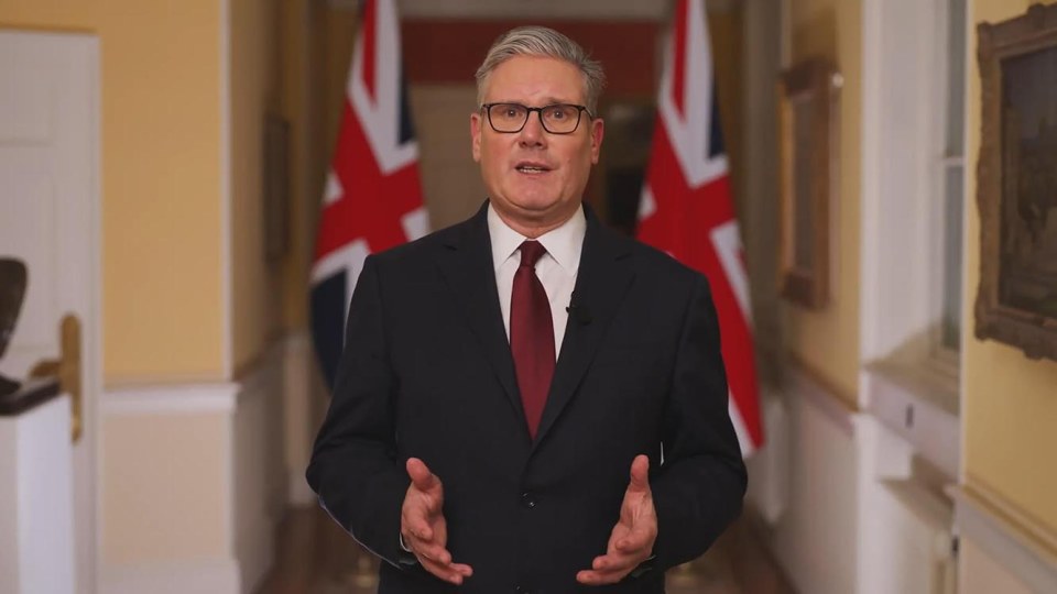 Keir Starmer speaking with two Union Jack flags behind him.