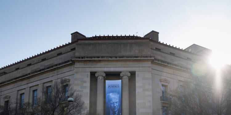 A banner of President Donald Trump hangs outside the U.S. Department of Justice on Saturday, March 21, 2026, in Washington, D.C.