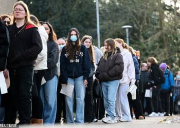 People, mainly students, queue to receive Meningitis B vaccinations at a sports centre on the University of Kent campus