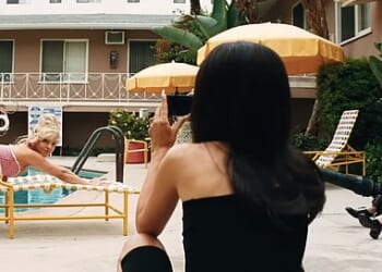 Posing on her hands and knees, Sydney Sweeney's character Cassie is seen bending back and forth as she locks eyes with the camera, held by Alexa Demie's character, Maddy
