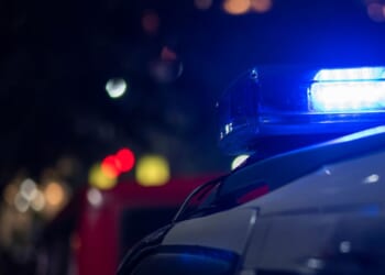 Lights flash on top of an emergency vehicle speeding down the road at night.