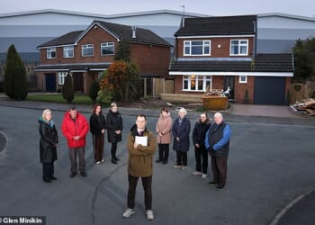 Guy Adams, front, with, from left, Ann Joe Littlewood, Paula Boardman, Dawn Hornby, Celia Spencer, Patricia Court, Jackie Peters and Steve Retford. The 60ft warehouse looms behind