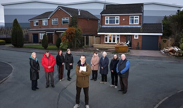 Guy Adams, front, with, from left, Ann Joe Littlewood, Paula Boardman, Dawn Hornby, Celia Spencer, Patricia Court, Jackie Peters and Steve Retford. The 60ft warehouse looms behind