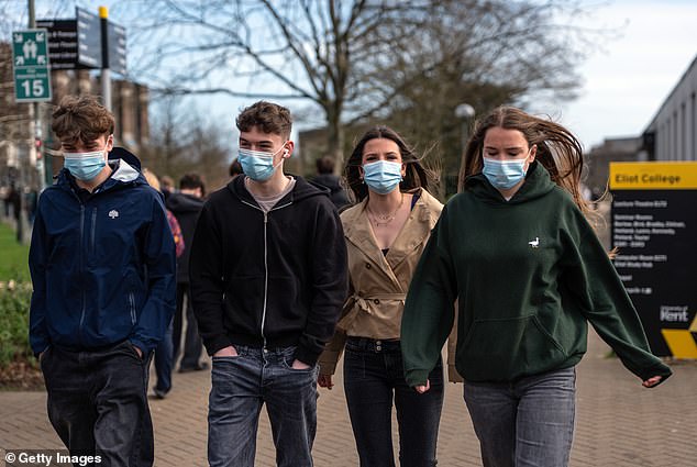 Students wearing face masks walk through the University of Kent campus in Canterbury on Monday