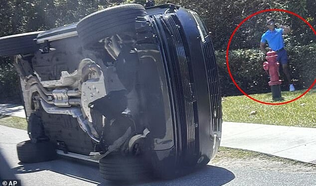 Tiger Woods stands alongside his Range Rover SUV after clambering out of the passenger side