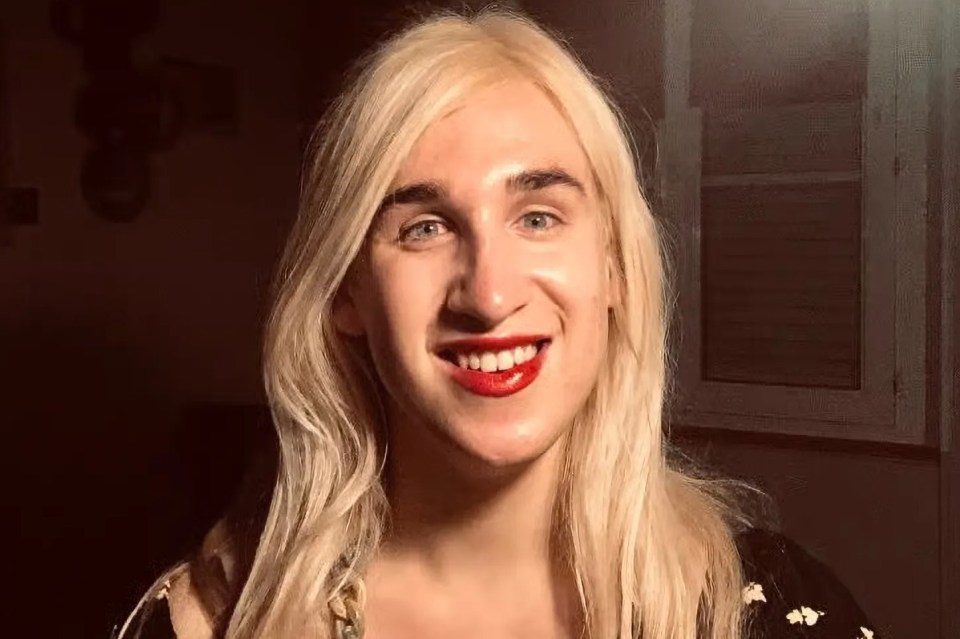 Vivienne Taylor, a trans woman with long blonde hair and red lipstick, smiles at the camera.