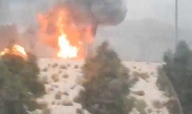 Smoke and flames rise from the South Pars gas field following an Israeli strike, as seen through the window of a moving vehicle
