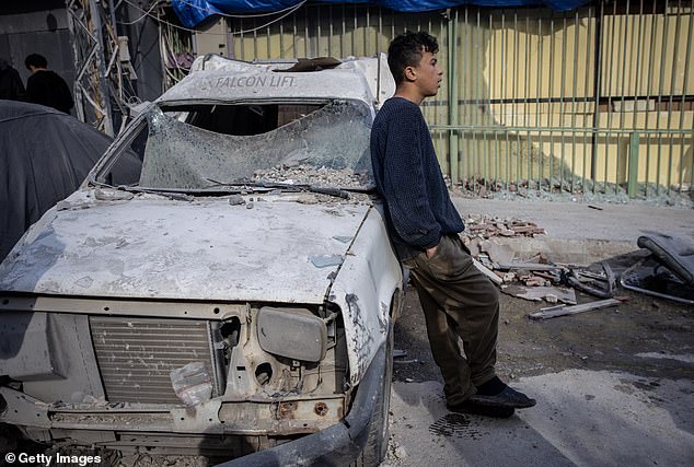 A boy leans on a car damaged in an Israeli airstrike in Beirut on Monday. The Iran war has caused gas prices to spike, with the national gas price average in the United States already increasing by $1 per gallon since the beginning of the Iran war